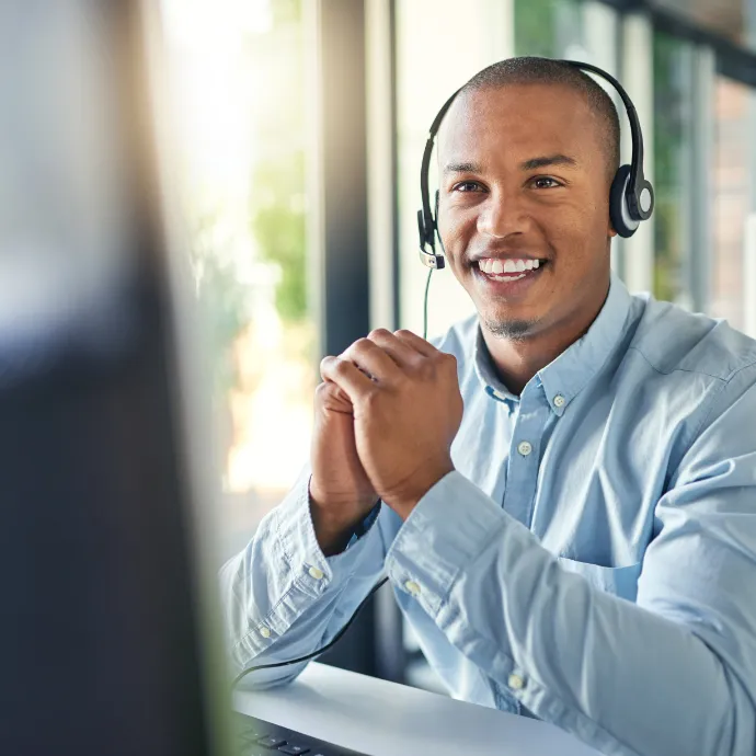 A happy young man in customer support wearing a phone headset